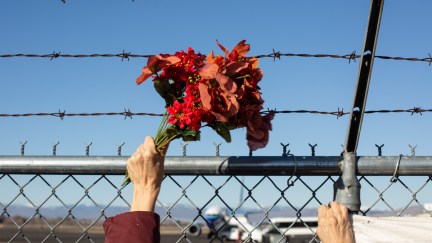 Activists from Yakima Immigrant Response Network wave flowers in front of a barbed wire fence.