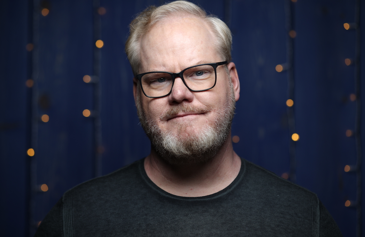 Jim Gaffigan in front of a blue background, looking at the camera.