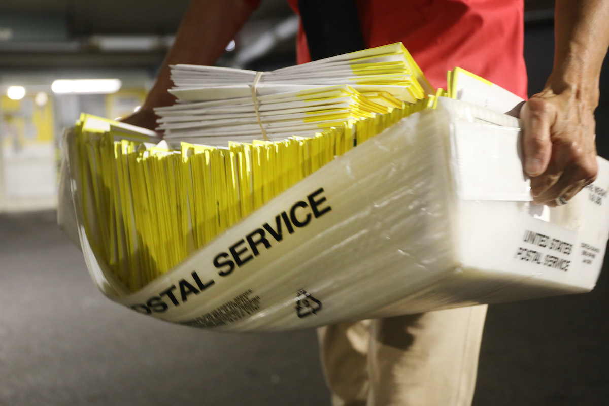 A polling worker holds 2020 presidential primary ballots that were dropped at a post office
