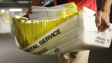 A polling worker holds 2020 presidential primary ballots that were dropped at a post office
