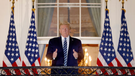 Donald Trump gives a double thumbs up outside the White House with no mask on.