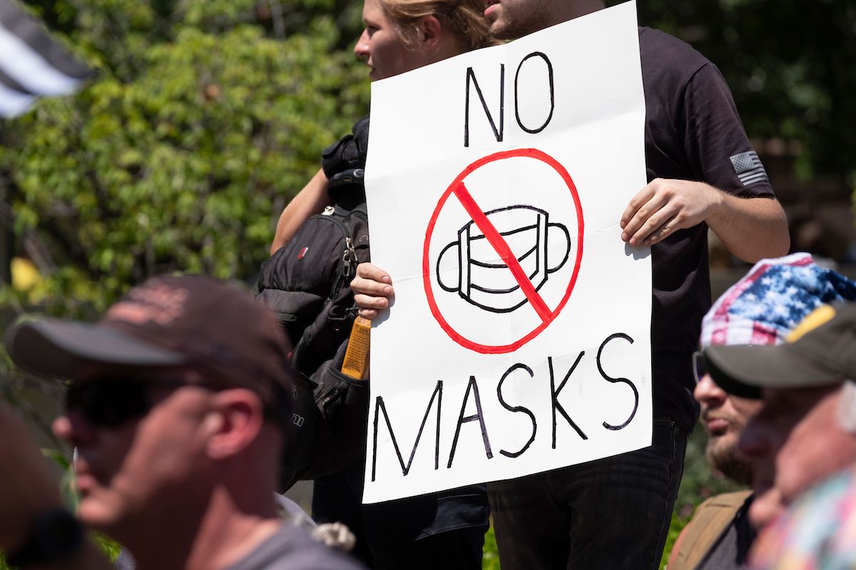 An anti-mask protestor holds up a sign in front of the Ohio Statehouse