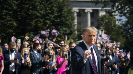 Donald Trump gestures as White House interns cheer him on as he leaves the White House residence