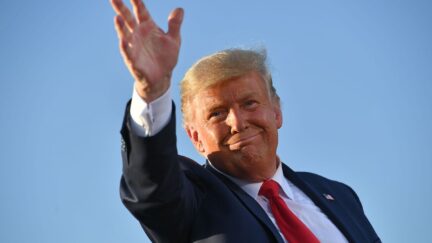 Trump waves and smirks outside.