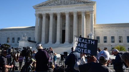 A demonstrator holds a sign in front of the US Supreme Court in Washington, DC, on November 10, 2020, as the high court opened arguments in the long-brewing case over the constitutionality of the 2010 Affordable Care Act, under which then-president Barack Obama's government sought to extend health insurance to people who could not afford it. - President Donald Trump's outgoing administration took aim in the US Supreme Court Tuesday at razing the 