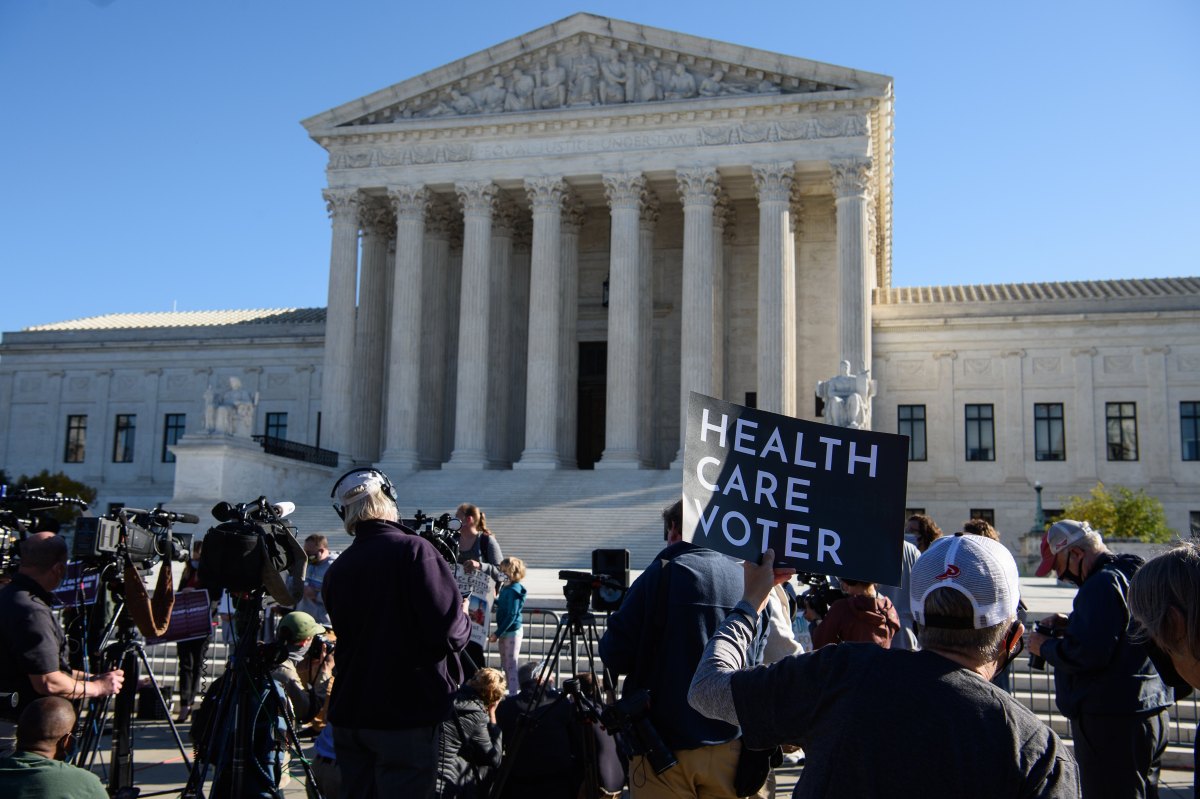 A demonstrator holds a sign in front of the US Supreme Court in Washington, DC, on November 10, 2020, as the high court opened arguments in the long-brewing case over the constitutionality of the 2010 Affordable Care Act, under which then-president Barack Obama's government sought to extend health insurance to people who could not afford it. - President Donald Trump's outgoing administration took aim in the US Supreme Court Tuesday at razing the "Obamacare" health program his predecessor built, a move which could cancel the health insurance of millions in the middle of the Covid-19 pandemic. (Photo by NICHOLAS KAMM / AFP) (Photo by NICHOLAS KAMM/AFP via Getty Images)