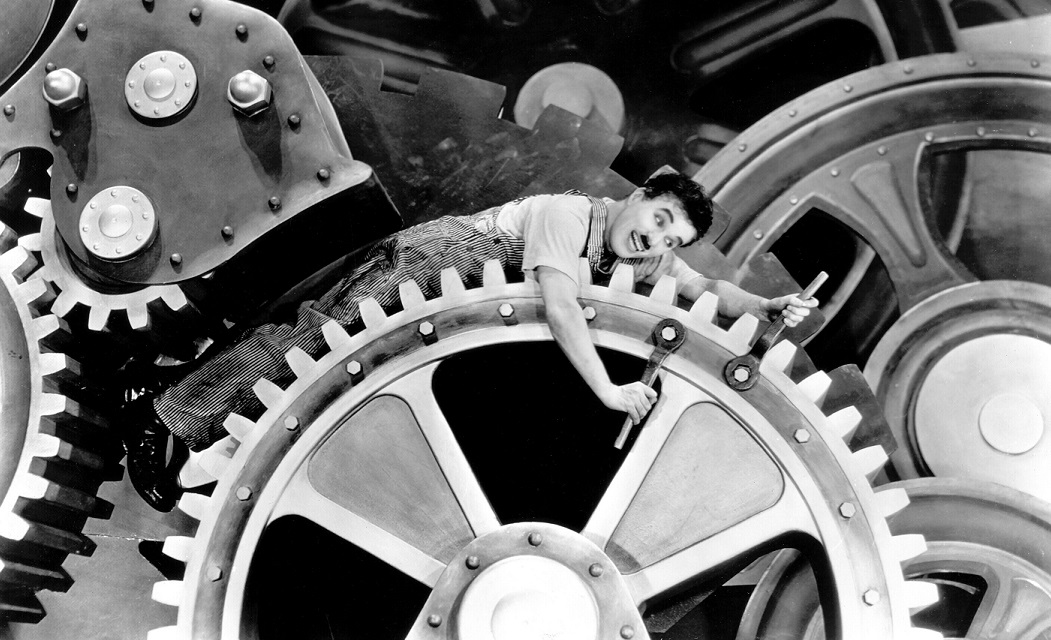 Charlie Chaplin as a factory worker caught in giant gears in Modern Times