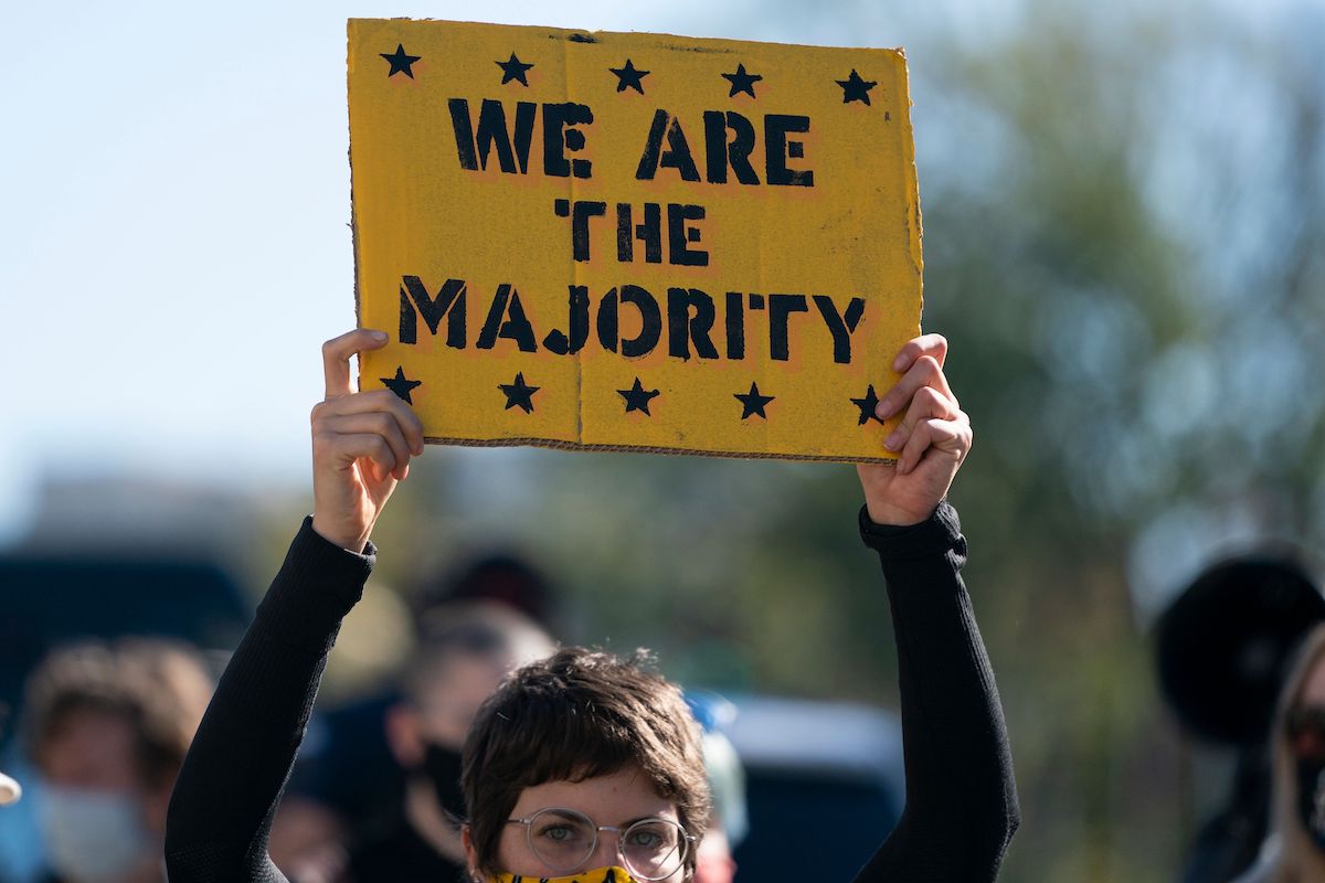 A protester holds a sign reading 'we are the majority.'