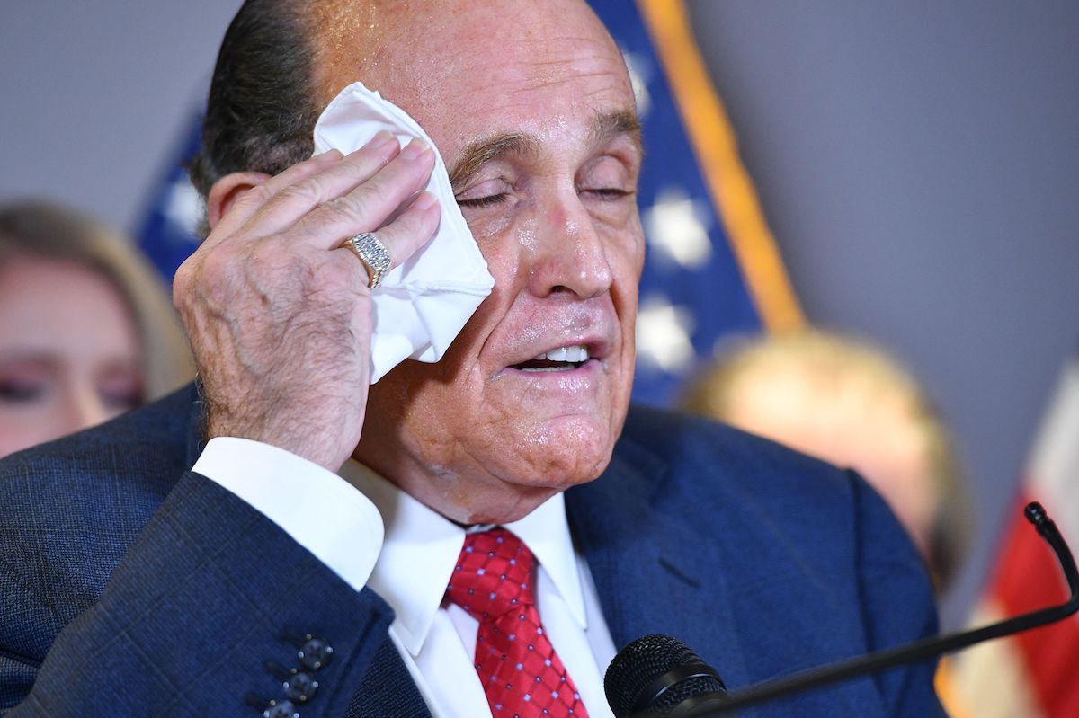 Rudy Giuliani wipes his sweaty face with a handkerchief during a press conference.