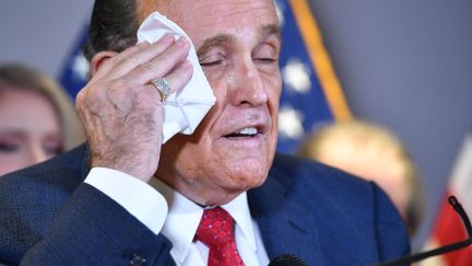 Rudy Giuliani wipes his sweaty face with a handkerchief during a press conference.