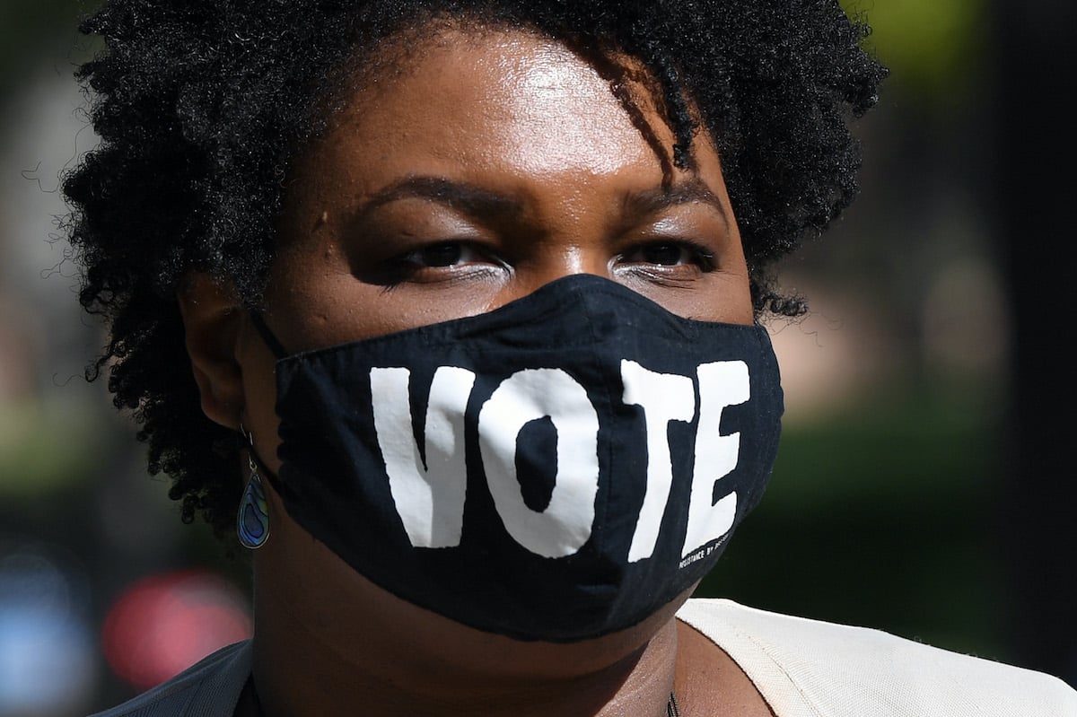 Stacey Abrams wears a face mask reading "VOTE"