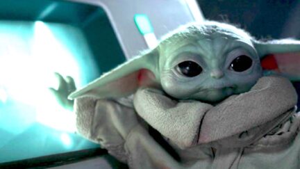 Grogu with his hand on a security camera screen on Disney+'s The Mandalorian.