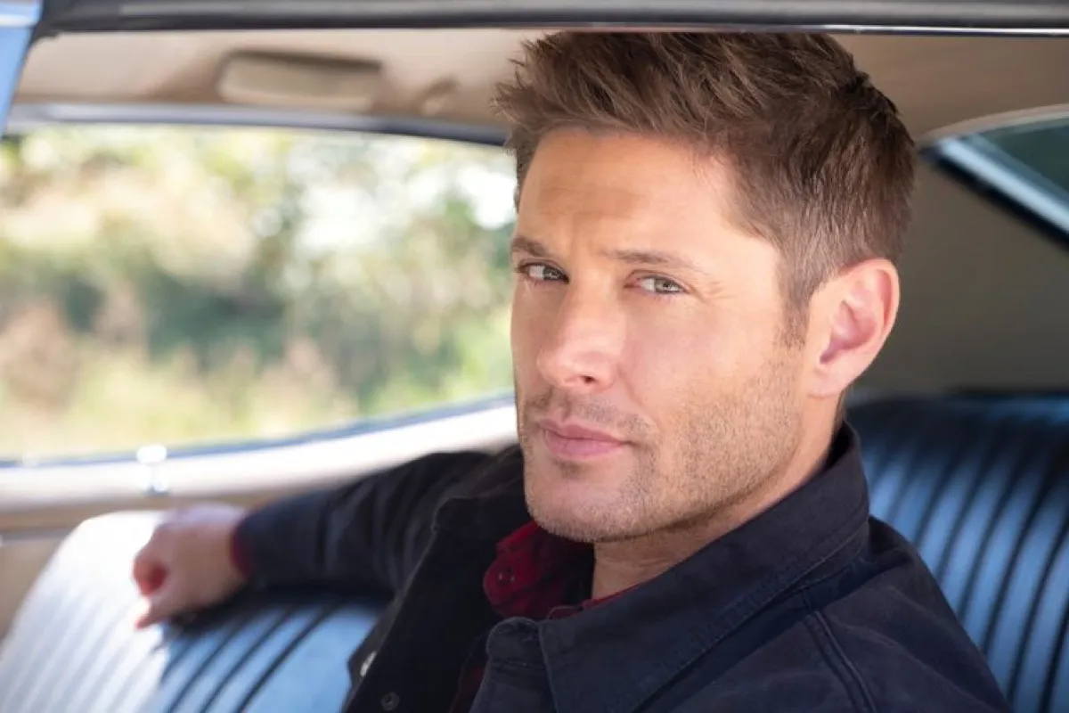 Dean Winchester sitting in the driver's seat of his car, smoldering at the camera in "Supernatural"