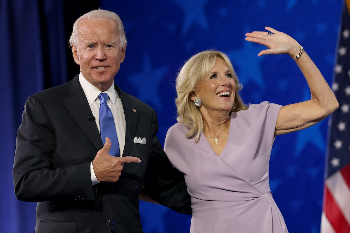 Joe Biden points to his wife Dr Jill Biden as she waves from a stage.