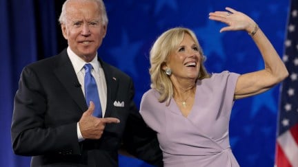 Joe Biden points to his wife Dr Jill Biden as she waves from a stage.