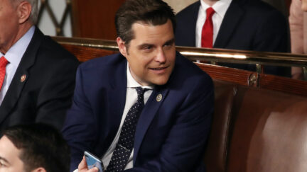 Matt Gaetz smirks while holding his phone.