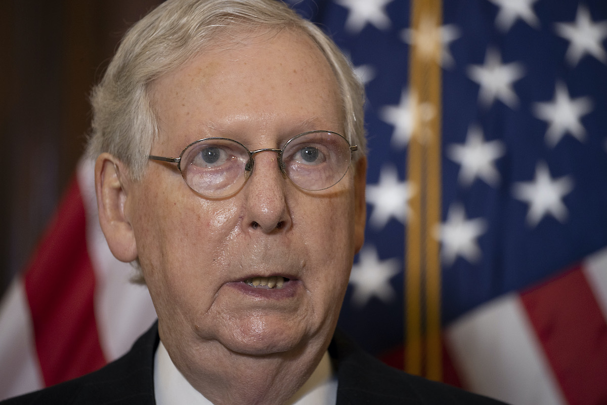 A close-up of Mitch McConnell sweating in front of an American flag.