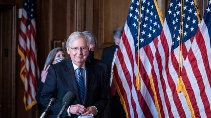 Mitch McConnell smirks as he enters for a press conference.