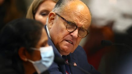 Rudy Giuliani cringes while listening to a masked poll worker give testimony in Michigan.