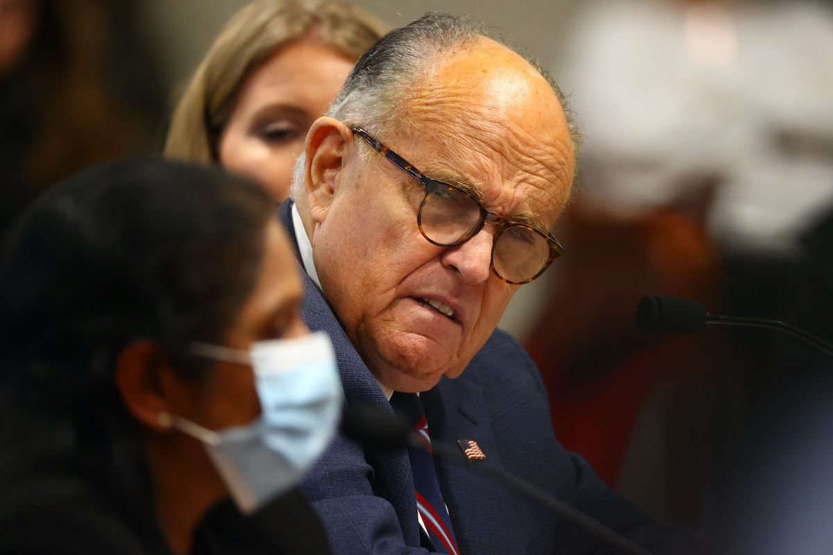 Rudy Giuliani cringes while listening to a masked poll worker give testimony in Michigan.