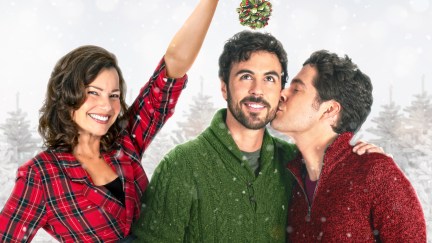 a mom holds mistletoe over her son and his boyfriend