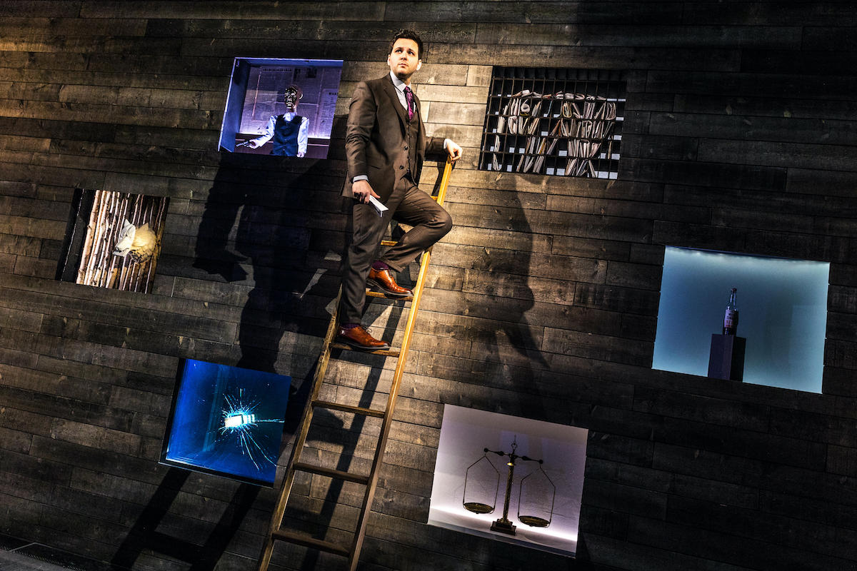 Derek DelGaudio at the top of a ladder on stage for In & Of Itself