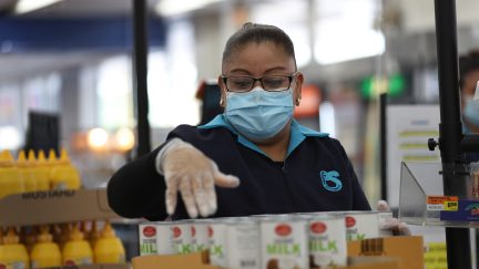 MIAMI, FLORIDA - APRIL 13: Lorena Martinez wears a mask and gloves as she works as a cashier at the Presidente Supermarket on April 13, 2020 in Miami, Florida. The employees at Presidente Supermarket, like the rest of America's grocery store workers, are on the front lines of the coronavirus pandemic, helping to keep the nation's residents fed. (Photo by Joe Raedle/Getty Images)