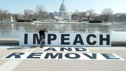 People gather at the base of the U.S. Capitol with large IMPEACH and REMOVE signs