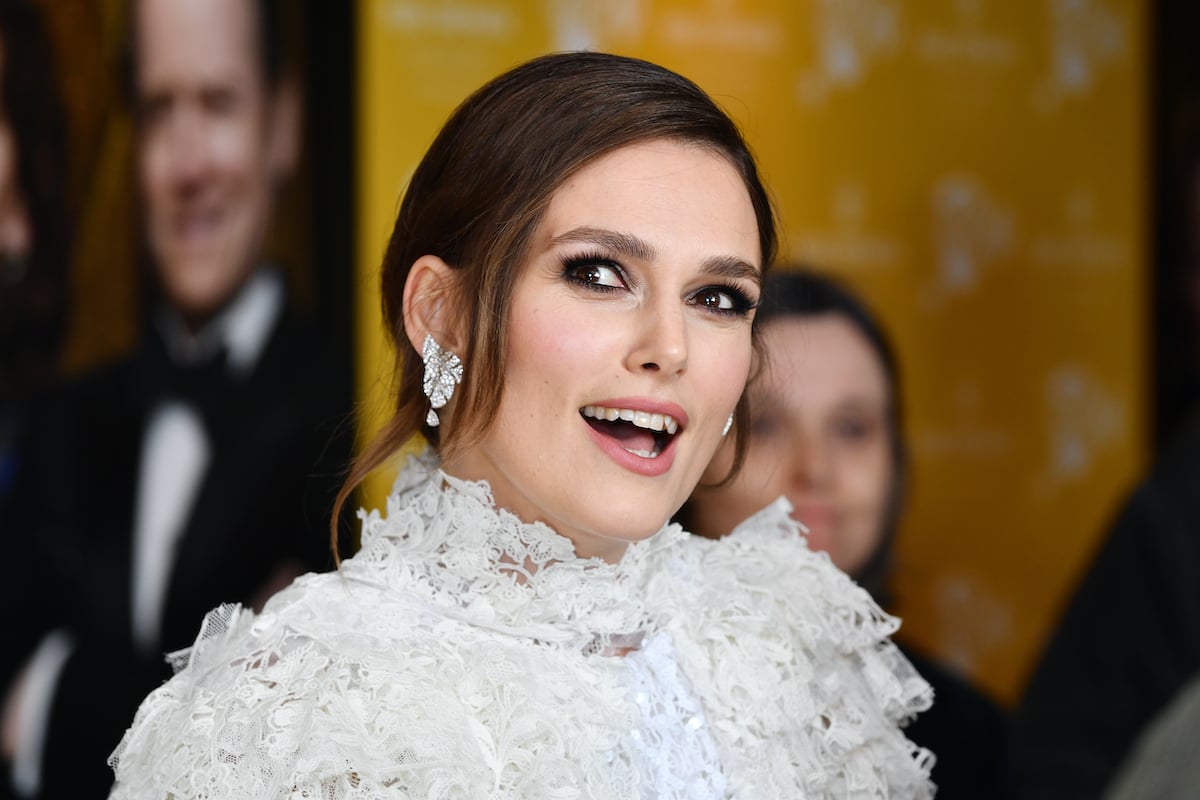 Keira Knightley wears an elaborate white dress on a red carpet.