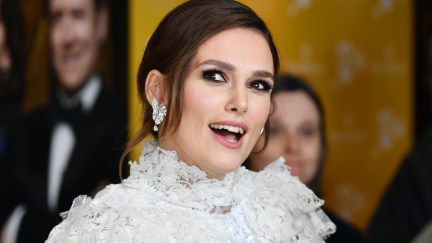 Keira Knightley wears an elaborate white dress on a red carpet.