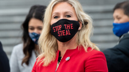 Rep. Marjorie Taylor Greene looks at the camera while wearing a black mask reading 
