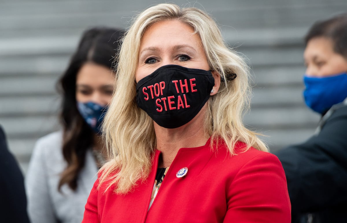 Rep. Marjorie Taylor Greene looks at the camera while wearing a black mask reading "Stop the Steal" in red letters.