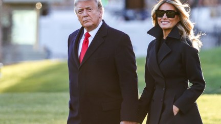 Donald and Melania Trump hold hands outdoors.