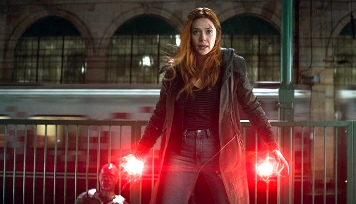 Elizabeth Olsen as Wanda Maximoff/Scarlet Witch fiercely guarding Paul Bettany's Vision with glowing red palms in Marvel's Avengers: Infinity War.