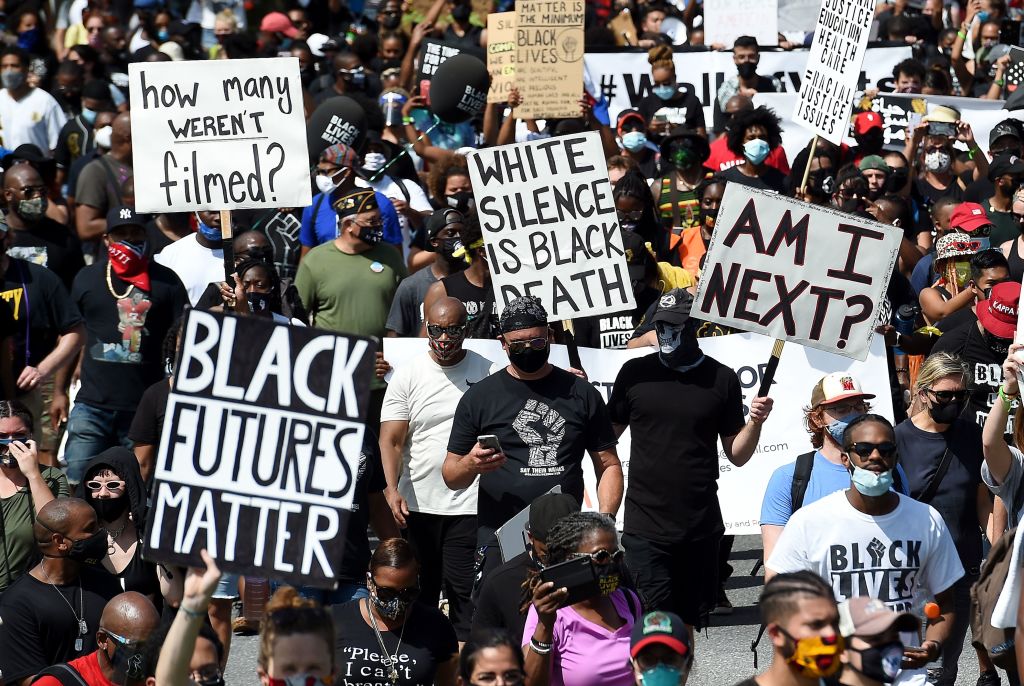People hold placards at the Lincoln Memorial s they attend the "Commitment March: Get Your Knee Off Our Necks" protest against racism and police brutality, on August 28, 2020, in Washington, DC. - Anti-racism protesters marched on the streets of the US capital on Friday, after a white officer's shooting of African American Jacob Blake. The protester also marked the 57th anniversary of civil rights leader Martin Luther King's historic "I Have a Dream" speech delivered at the Lincoln Memorial. (Photo by Olivier DOULIERY / AFP) (Photo by OLIVIER DOULIERY/AFP via Getty Images)