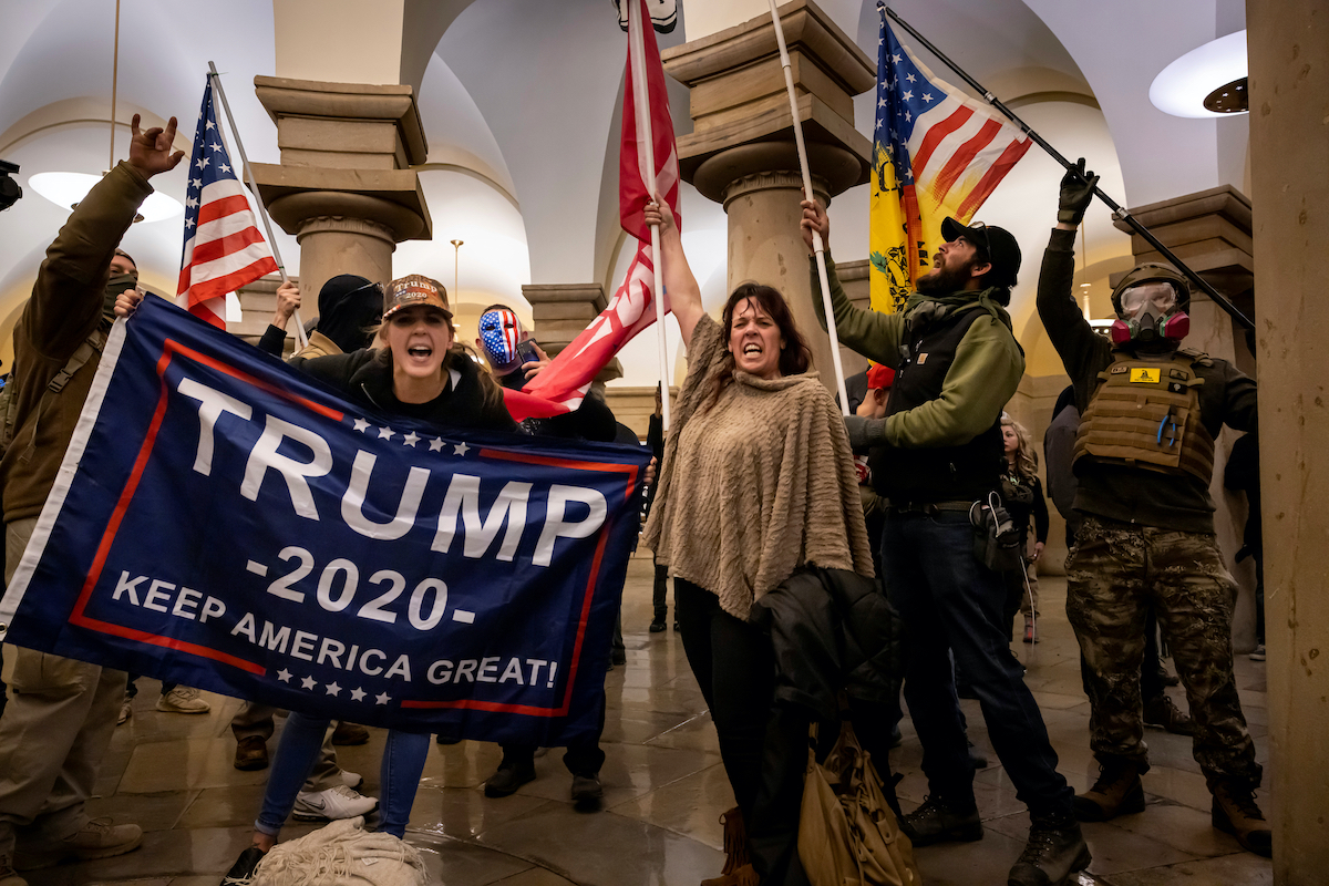 Trump supporters wave a Trump 2020 flag during the Capitol riot.