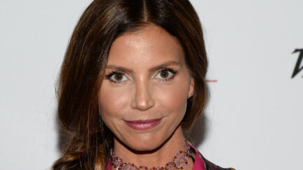 Charisma Carpenter looks at the camera while walking a red carpet for an event.