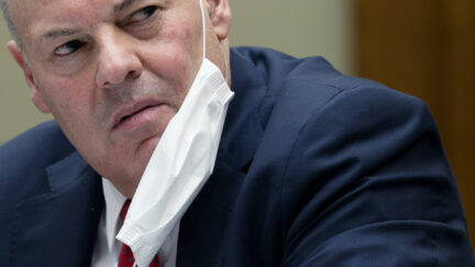 United States Postal Service Postmaster General Louis DeJoy looks angry with a mask hanging from his ear while testifying during a House Oversight and Reform Committee hearing