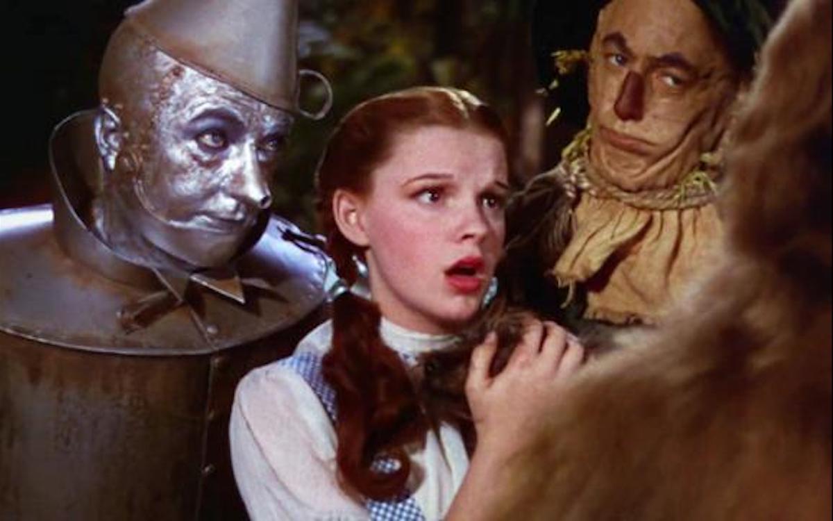 Dorothy, the Tin Man, and the Scarecrow look scared/disapproving in a still from The Wizard of Oz