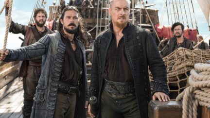 flint and silver look worried and dirty on the deck of a ship in black sails