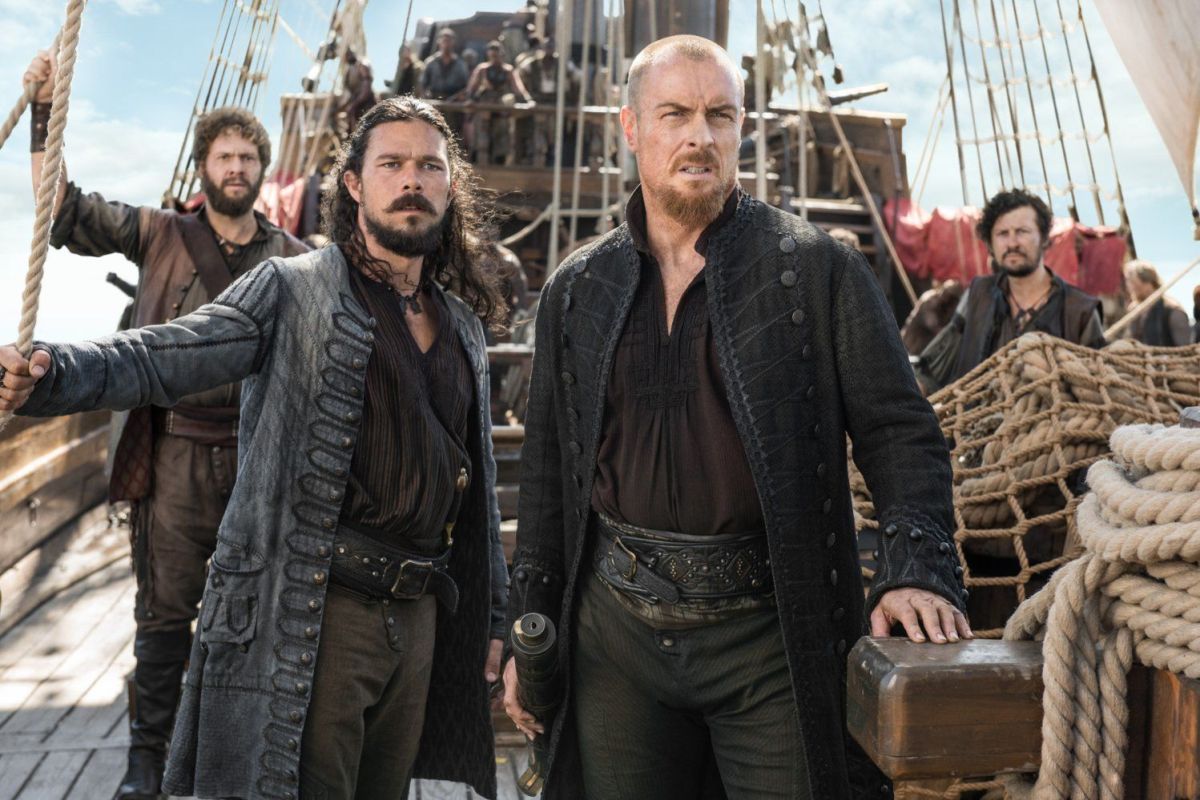 flint and silver look worried and dirty on the deck of a ship in black sails