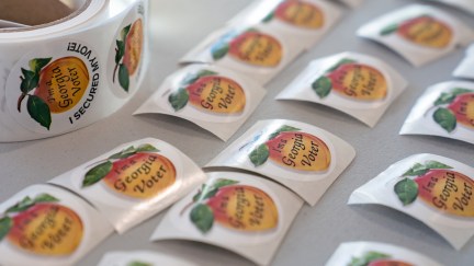 A table lined with Georgia voter stickers on a peach logo