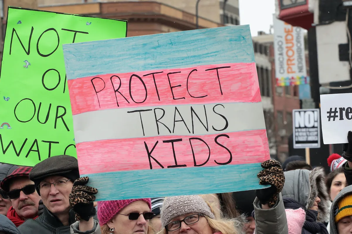 At a protest for transgender rights, a person holds a sign reading "Protect trans kids".