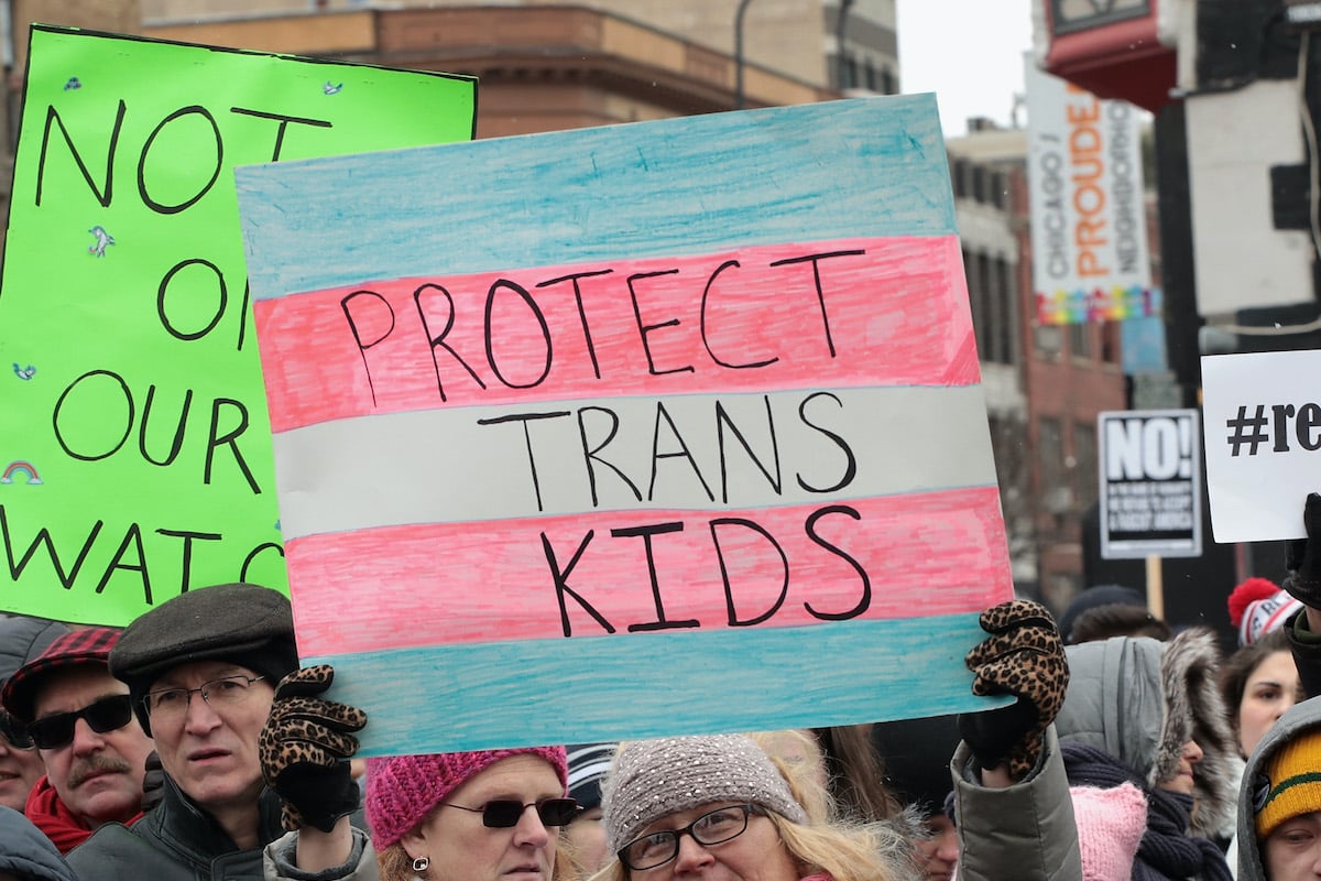 At a protest for transgender rights, a person holds a sign reading "Protect trans kids"