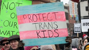 At a protest for transgender rights, a person holds a sign reading 