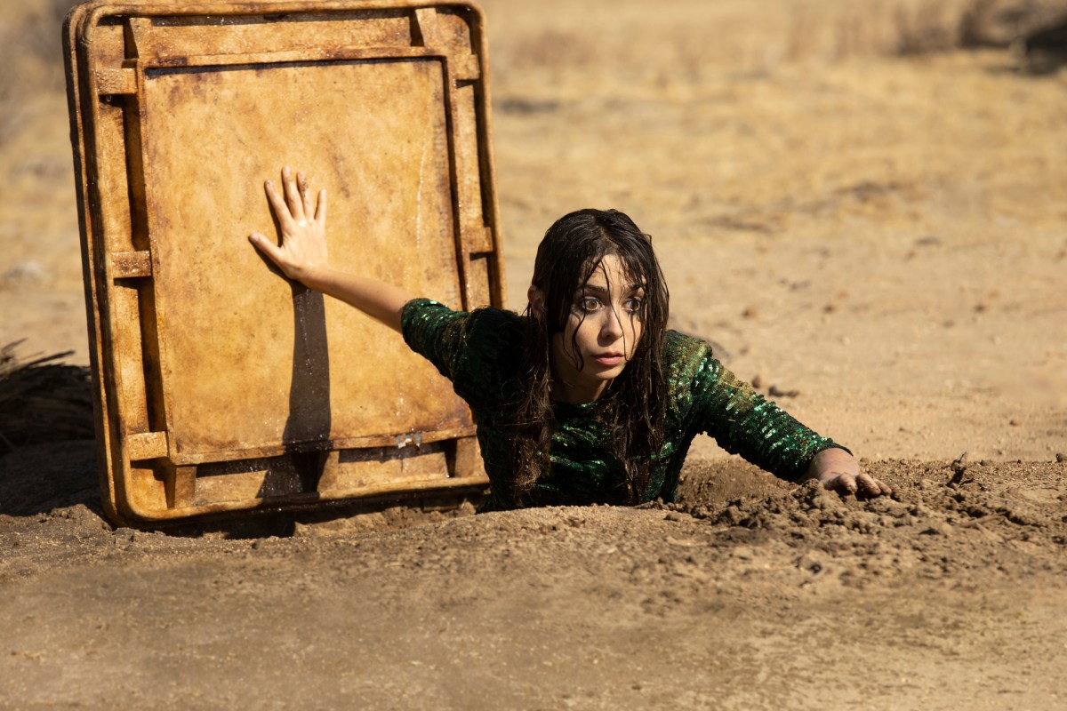 Cristin Milioti as Hazel in Made for Love, climbing out of the metal hatch to an underground waterway in the desert.
