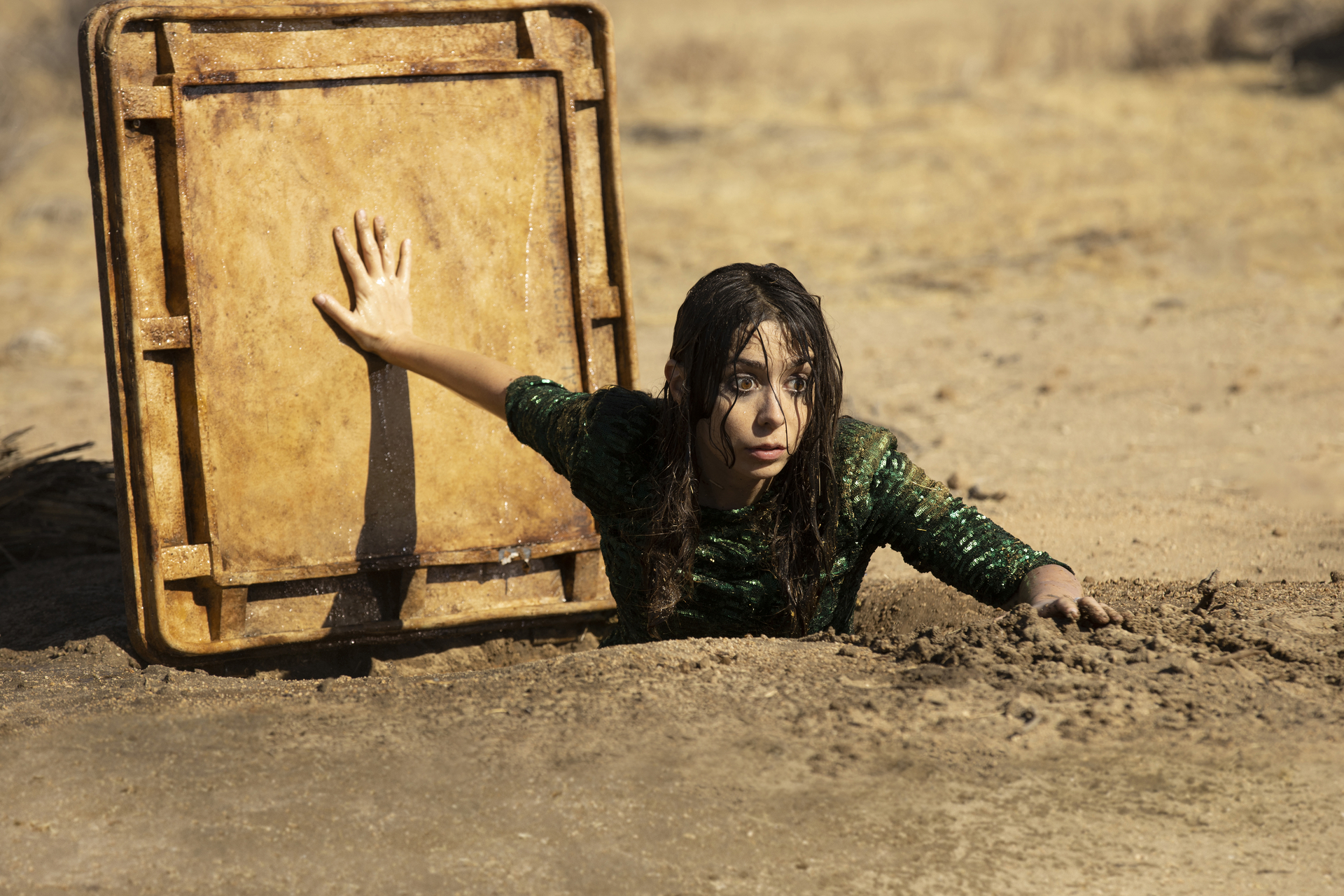 Cristin Milioti as Hazel in Made for Love, climbing out of the metal hatch to an underground waterway in the desert.