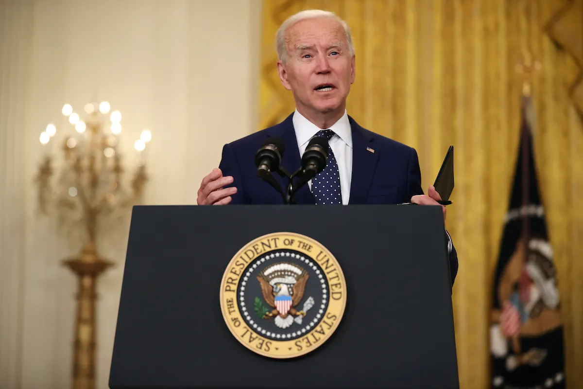 Joe Biden talks from a podium with the presidential seal