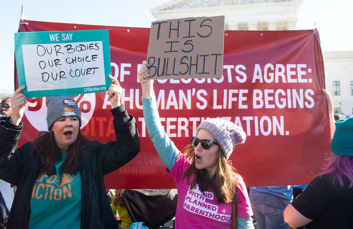 A pro-choice protester in a Planned Parenthood shirt holds a sign saying "This is bullshit"