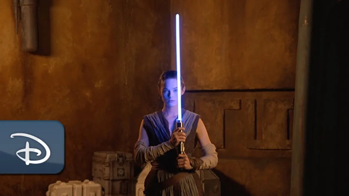 Rey lookalike holding Disney's new retractable lightsaber.